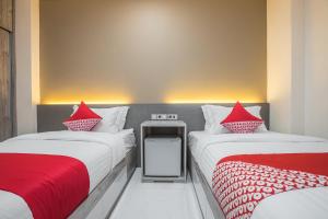 雅加达OYO 1487 Residence Khoe的客房内的两张床和红色枕头