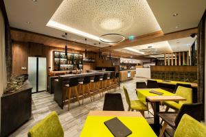伊施格尔Hotel Modern Mountain的一间设有黄色桌椅的餐厅和一间酒吧