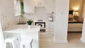 开普敦Carrington Cottage的白色的厨房设有水槽和炉灶。