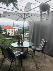 第比利斯Apartment Lui的阳台配有一张桌子和两把椅子以及一把遮阳伞。