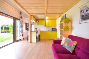 DomneştiHappy Place - Casuta Galbena的一间带紫色沙发的客厅和一间厨房