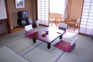 妙高赤仓久井酒店的客厅配有桌椅和电视。