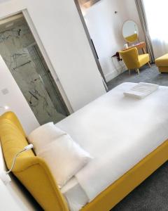 伦敦Widegate Residential的一张大床,位于一个黄色椅子的房间