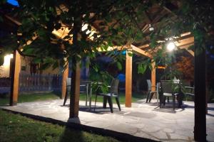TaranesHotel Rural Llerau的庭院配有椅子和桌子,晚上还种有树木