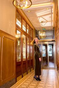 德帕内Hotel Royal的站在走廊上身穿黑色衣服的女人