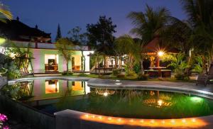 NegaraHOTEL SEGARA MANDALA的夜间在房子前面的游泳池