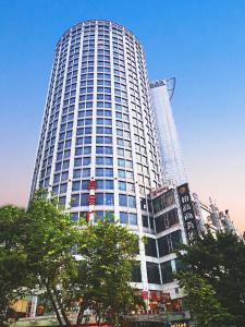 广州Paco Hotel Tuanyida Metro Guangzhou -Free ShuttleBus for Canton Fair的一座高大的白色建筑,前面有树木