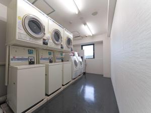 半田名铁赤塔半田市站前酒店的洗衣房,配有洗衣机和烘干机