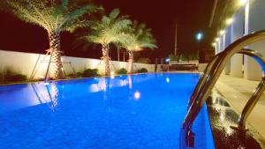 清迈Pleasant Chiangmai的夜间拥有棕榈树的蓝色游泳池