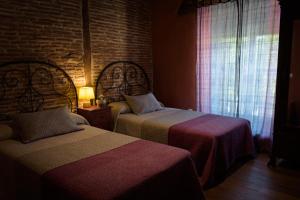 TraguntiaCasa Rural Caenia Grupos的一间卧室设有两张床和砖墙