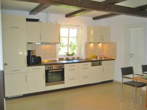 奔驰Ferienhaus Benz USE 081的厨房配有白色橱柜、烤箱和桌子。