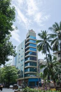 孟买Hotel Grace Galaxy的一座高大的建筑,前面有棕榈树