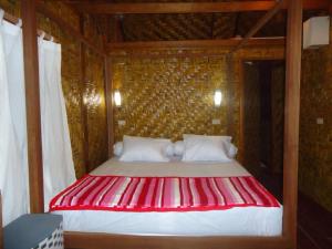 LasikinSimeulue Surflodges的木制客房内的红色和白色的床