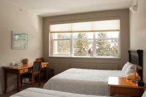 班夫班夫YWCA旅舍的一间卧室设有两张床、一张桌子和一个窗口。