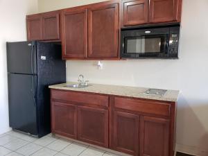 维多利亚十字路口套房旅馆的厨房配有木制橱柜和黑色冰箱。