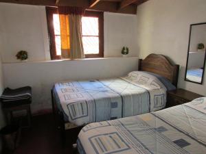 圣地亚哥Hostería Baños Morales的一间卧室设有两张床和两个窗户。