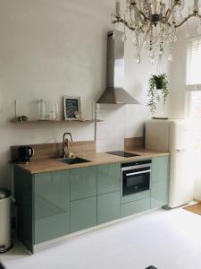 弗利辛恩Appartement Zeeuws genoegen的厨房配有绿色橱柜和吊灯。