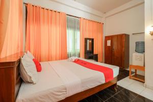 图克图克RedDoorz @ Tuktuk Danau Toba的一间卧室配有一张带橙色窗帘的床