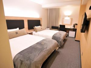 久留米市Green Rich Hotel Kurume Natural Hot Spring Arimamutsumonnoyu的酒店客房配有两张床和一张书桌