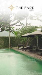 班达亚齐The Pade Hotel的一个带桌子和遮阳伞的绿色水池