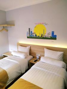 Rawabokor DuaCentral Front One Inn Jakarta Airport的酒店客房设有两张床,墙上挂有绘画作品