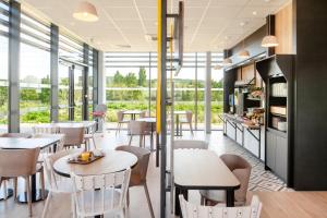伊尼B&B HOTEL Igny Palaiseau的餐厅设有桌椅和窗户。
