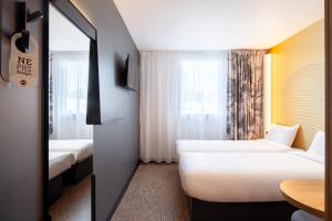 伊尼B&B HOTEL Igny Palaiseau的酒店客房设有两张床和一张桌子。