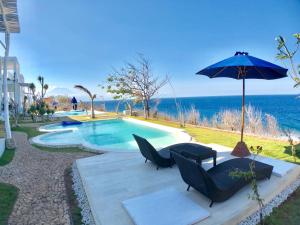 珀尼达岛Villa Argia Nusa Penida的毗邻大海的带椅子和遮阳伞的游泳池