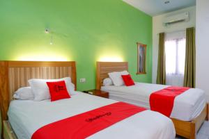 帕卢RedDoorz near Taman Makam Pahlawan Tatura的配有两张床铺的绿色墙壁和红色枕头