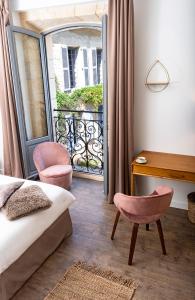 蒙蒂尼亚克Les chambres de l'ATELIER à Montignac Lascaux的一间带一张床和一张书桌的卧室以及一个阳台