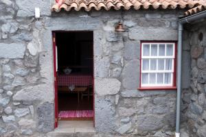 Fajã dos VimesCasas Dos Vimes的通往石头建筑的大门,有红色的窗户