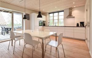ÅrøAwesome Home In Assens With Sauna, Internet And Indoor Swimming Pool的厨房以及带白色桌椅的用餐室。