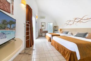 科斯塔卡玛Hotel LIVVO Risco del Gato Suites的酒店客房设有两张床和一台平面电视。