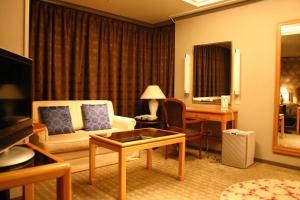 挂川市挂川大酒店的一间客厅,客厅配有沙发和一张书桌,位于酒店的房间