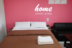 素叻素叻他尼机场NK花园酒店的一间卧室配有床、沙发和粉红色的墙壁