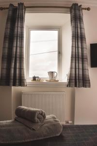 BowmoreTHE BRUCE的暖气上的带窗帘和毛巾的窗户
