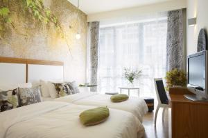 塞萨洛尼基城市酒店的一间卧室设有两张床、一台电视和一扇窗户。
