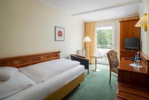 上乌瑟尔陶纳斯公园酒店的酒店客房配有一张床、一张书桌和一台电视。