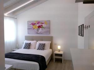 龙卡德Le Mandragole B&B的一间白色的卧室,配有一张床和花瓶