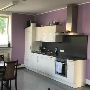 苏尔茨巴赫-罗森贝格Gästehaus Sandra的厨房配有白色橱柜和紫色墙壁