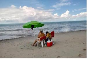 伊塔帕里卡Casa Ilha de Itaparica的两人坐在海滩上,被伞所环绕