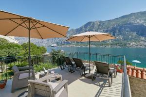 科托尔Mediterranean Holiday House & Apartments的一个带桌椅和遮阳伞的庭院