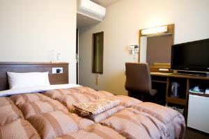 七尾南澳站前路线酒店的一间卧室配有一张床、一张书桌和一台电视