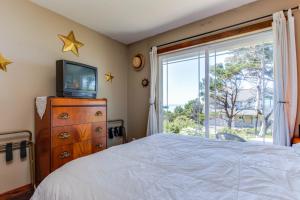 Holiday BeachOregon Bed n' Beach的一间卧室设有一张床、一台电视和一个窗口。