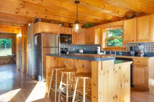 法兰克尼亚Private Franconia Log Cabin的厨房配有木制橱柜和带凳子的台面