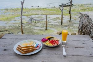 蓝梦岛Wooden Beach Sunset Cottages的一张桌子,上面放着两盘早餐食品和一杯橙汁