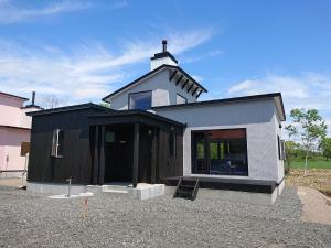 鹤居村Tsukushi Village的一间黑色和白色的小房子,屋顶