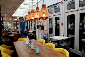 SomerenHotel Centraal的餐厅设有木桌和黄色椅子