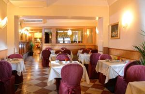 威尼斯里亚托桥酒店的餐厅配有白色桌子和紫色椅子