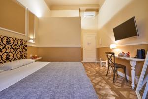佛罗伦萨勒司坦泽教堂广场住宿加早餐酒店的酒店客房设有一张床、一张书桌和一台电视机。